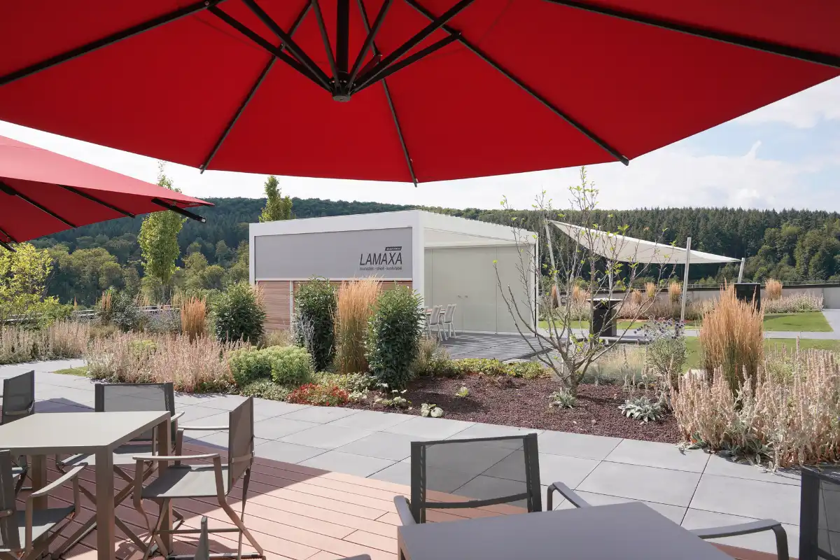 Moderne Gartenlandschaft mit Lamaxa Terrassenüberdachung und roten Sonnenschirmen