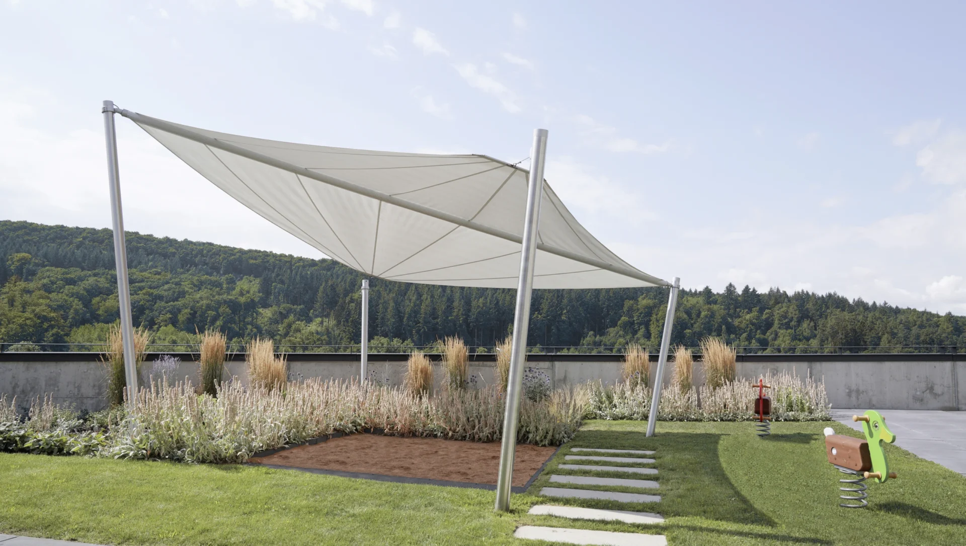 Moderne Sonnensegel über einem Spielbereich mit grüner Landschaft im Hintergrund